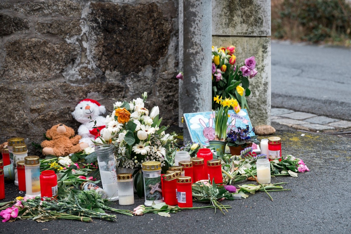 Kerzen und Blumen an einer Mauer vor dem Kinder- und Jugendhilfezentrum in Wunsiedel, in dem die Zehnjährige tot aufgefunden wurde.
