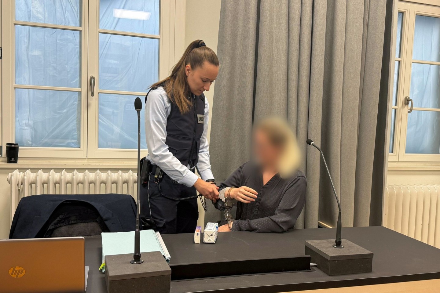 Eine Justizmitarbeiterin nimmt der Angeklagten beim Prozessauftakt vor dem Landgericht Ravensburg die Handschellen ab.